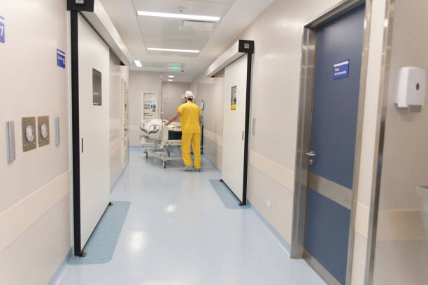 A male nurse pushing hospital gurney with patient along hospital corridor.